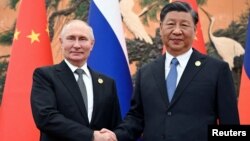 资料照片：俄罗斯总统普京在北京出席“一带一路”国际合作高峰论坛时与中国国家主席习近平握手。（2023年10月18日）。