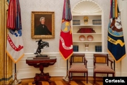 Conjunto decorativo con banderas del servicio militar, un cuadro del expresidente Andrew Jackson una escultura en bronce conocida como “Bronco Buster” de Frederic Remington, que también adornó la primera Oficina Oval de Trump.