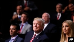 Donald Trump (devan) nan mitan 2 pitit li: Donald Trump, Jr. (agoch) ak Ivanka Trump (adwat) pandan yon lòt pitit gason Eric Trump tap pran lapawòl devan degele yo sou 3èm jou konvansyon an mèkredi 20 jiyè 2016 la. 