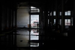 A fire official is shown reflected in a puddle in a warehouse after a fire broke out before dawn at Fisherman's Wharf in San Francisco, May 23, 2020.