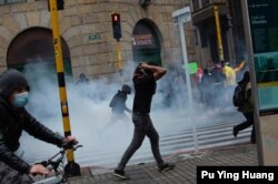 Demonstrators run away from tear gas during a national protest against tax reform in Bogotá, Colombia, April 28, 2021. (Pu Ying Huang/VOA)