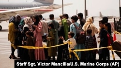 Sur cette photo fournie par les Marines américains, des civils se préparent à monter dans un avion lors d'une évacuation à l'aéroport international Hamid Karzai de Kaboul, en Afghanistan, mercredi 18 août 2021.