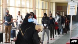 Passengers wearing a protective mask walk-in at the Jomo Kenyatta international airport in Nairobi, on August 1, 2020, as Kenya Airways airline resumed flights to Britain after flights had been canceled during the COVID-19 outbreak.