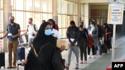 Passengers wearing a protective mask walk-in at the Jomo Kenyatta international airport in Nairobi, on August 1, 2020, as Kenya Airways airline resumed flights to Britain after flights had been canceled during the COVID-19 outbreak.