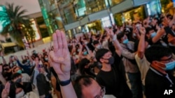 Pro-democracy activists flash three-fingered salute while listening to the national anthem outside Siam Paragon, one of the largest shopping malls, in Bangkok, Thailand, Oct. 20, 2020.