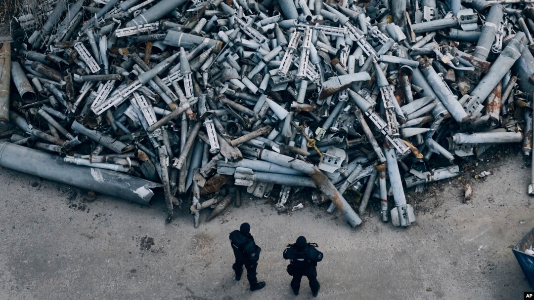 Oficiales de policía miran fragmentos recolectados de los cohetes rusos que impactaron en Kharkiv, Ucrania, el sábado 3 de diciembre de 2022. (Foto AP/Libkos)