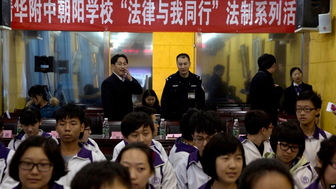 Government workers stand under a banner that reads "Tsinghua-affiliated Chaoyang School, The Law and me together, legal series of talks" as they observe a student meeting on legal matters on Constitution Day in Beijing, Dec. 4, 2014.
