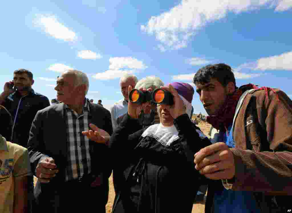 Turkish Kurds watch the fighting between Islamic militants and Kurdish forces to the west of Kobani, Syria, at the Turkey-Syria border near Suruc, Turkey, Sept. 30, 2014. 