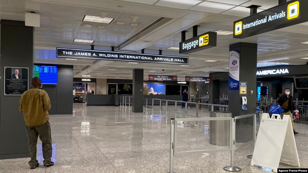 FILE - Travelers walk in a quiet arrivals terminal at Washington Dulles International Airport in Dulles, Virginia, Nov. 19, 2020. 
