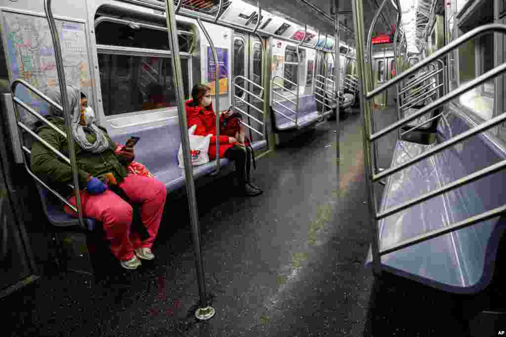 Subway riders wear protective masks and gloves on a sparsely populated car during morning hours due to COVID-19 concerns that are driving down ridership, March 19, 2020, in New York.