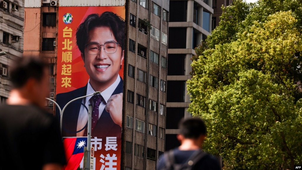 2026年10月15日，行人走过台北市一块巨大的竞选广告牌，广告牌上印有民进党台北市长候选人沈伯洋的头像。
