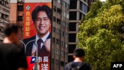 2026年10月15日，行人走过台北市一块巨大的竞选广告牌，广告牌上印有民进党台北市长候选人沈伯洋的头像。
