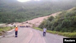 Gambar warga setempat sedang memeriksa lokasi longsor dan kerusakan di sebuah jalan dekat Kota Tabubil setelah gempa di Dataran Tinggi Selatan di Papua Nugini, 26 Februari 2018. (Jerome Kay/Handout via Reuters)