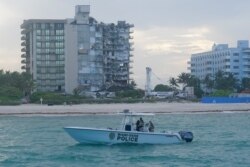 A Miami-Dade County Police boat patrols the ocean in front of the partially collapsed Champlain Towers South condo building in Surfside, Florida, July 4, 2021.