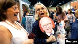 Shareholders Deborah Kiel, left, and Laura Flynn react to a Warren Buffett fan at the Berkshire Hathaway Inc. annual meeting, the largest in corporate America, in its hometown of Omaha, Neb., May 4, 2018.