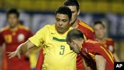 Brazil's retired striker Ronaldo (L) fights for a ball with Romania's Iasmin Latovlevici during his farewell soccer match with the Brazilian team, a friendly with Romania, in Sao Paulo, June 7, 2011