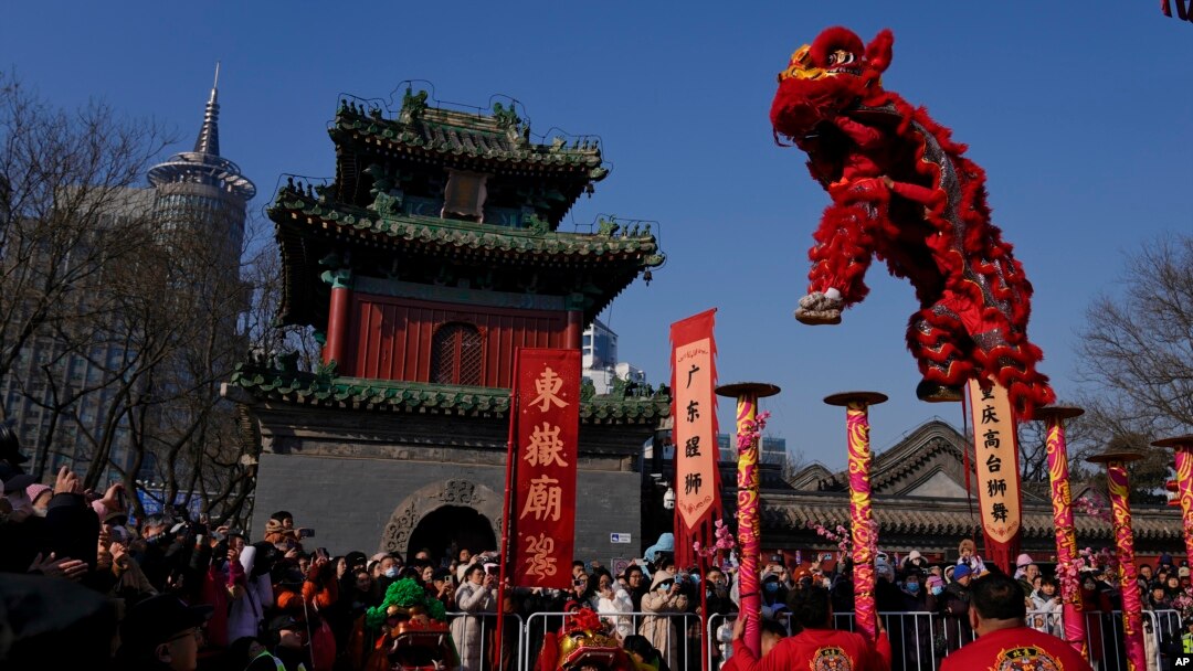 People watch as an artist performs an acrobatic lion dance at the Dongyue Temple on the first day of the Chinese Lunar New Year in Beijing on Jan. 29, 2025.