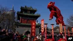 People watch as an artist performs an acrobatic lion dance at the Dongyue Temple on the first day of the Chinese Lunar New Year in Beijing on Jan. 29, 2025.