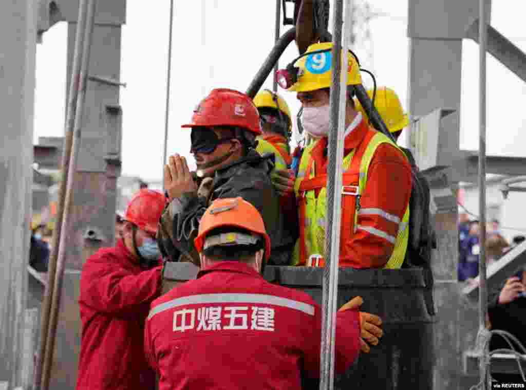 Rescue workers help a miner as he is brought to the surface at the Hushan gold mine after the January 10 explosion trapped workers underground, in Qixia, Shandong province, China. (Credit: cnsphoto)
