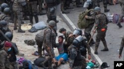 A Honduran migrant is tended to by Guatemalan soldiers after migrants clashed with them in a bid to cross the border in Vado Hondo, Guatemala, in a quest to eventually reach the United States, Jan. 17, 2021.