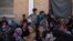 FILE - Women and children from Hawija sit outside a Kurdish screening center to determine if they were associated with the Islamic State group, in Dibis, Iraq, Oct. 3, 2017.