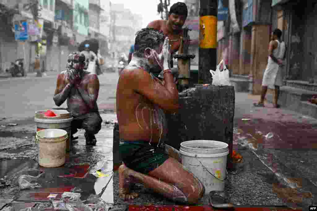 Men bathe along a street on a cold smoggy morning in the old quarters of New Delhi.