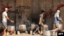Orang-orang memasak dengan kayu bakar untuk menyediakan makanan bagi pengungsi Palestina di tengah menipisnya pasokan bahan bakar minyak dan gas pada saat serangan Israel di Khan Yunis, selatan Jalur Gaza, 15 Oktober 20223. (Foto: MAHMUD HAMS / AFP)