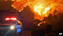 In this photo provided by the Santa Barbara County Fire Department, fire burns canyons and ridges above Bella Vista Drive near Romero Canyon as the fight to contain a wildfire continues in Montecito, Calif., Tuesday, Dec. 12, 2017.