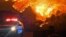 In this photo provided by the Santa Barbara County Fire Department, fire burns canyons and ridges above Bella Vista Drive near Romero Canyon as the fight to contain a wildfire continues in Montecito, Calif., Tuesday, Dec. 12, 2017.