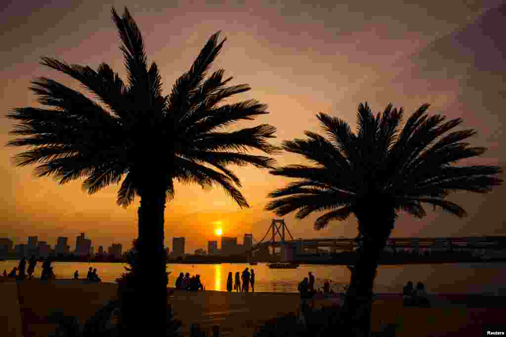 The sun sets over Tokyo Bay in Tokyo, Japan, seen from Odaiba beach.