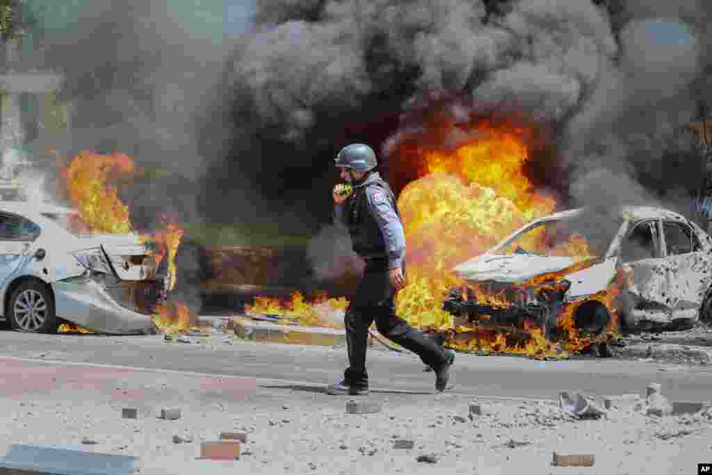 An Israeli firefighter walks next to cars hit by a missile fired from Gaza Strip, in the southern Israeli town of Ashkelon.