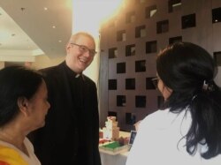 The Rev. Walter Kedjierski, who spoke at the volunteer event, smiles as volunteers explain plans for a hospital that SLRC is also trying to build. (Leslie Bonilla/VOA)