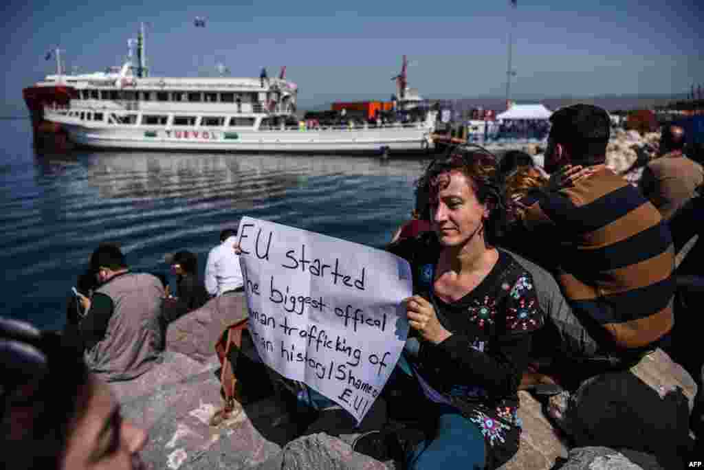 ترکی کی بندر گاہ پر ایک عورت نے احتجاجاً پلے کارڈ اٹھا رکھا ہے۔