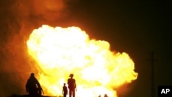 Egyptians watch as smoke and flames rise into the air after masked gunmen blew up a terminal of the Egyptian natural gas pipeline to Israel and Jordan in el-Arish, in the northern part of Egypt's Sinai Peninsula, in a predawn attack, July 12, 2011.