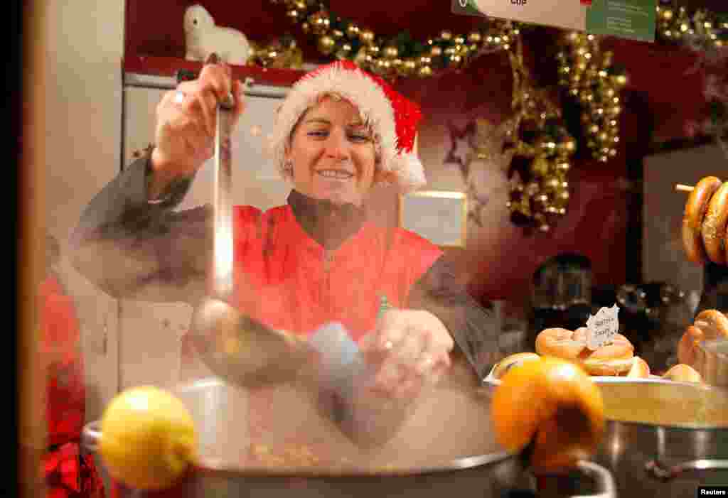 Una vendedora ambulante sirve vino caliente en el mercado navide&#241;o cerca de la catedral de Estrasburgo, Francia. [Reuters].