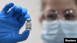 Seorang petugas kesehatan memegang botol vaksin COVID-19 produksi Pfizer / BioNTech, di Guy's Hospital, London, Inggris, 8 Desember 2020. (Foto: dok).