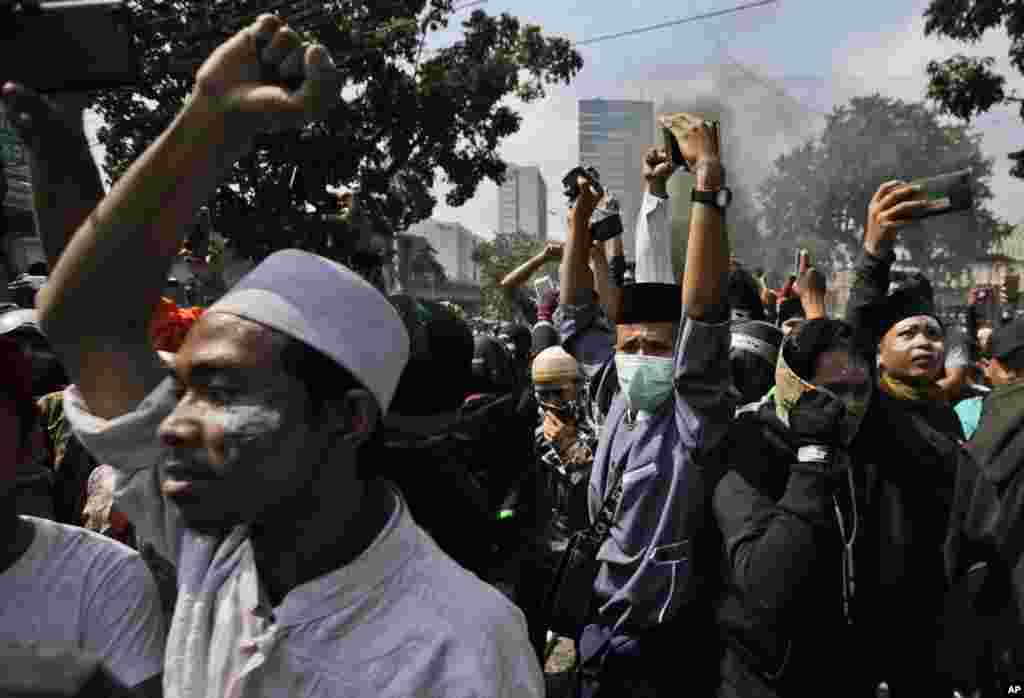 Massa pendukung capres Prabowo Subianto mengacungkan kepalan tangan dalam bentrokan dengan polisi di Jakarta, Rabu, 22 Mei 2019. (Foto: Dita Alangkara/AP)