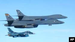 In this photo released by Japan Air Self Defense Force, U.S. Air Force B-1B bombers, top, fly with a Japan Air Self Defense Force F-2 fighter jet over Japan's southern island of Kyushu, just south of the Korean Peninsula, during a Japan-U.S. joint exercise, July 30, 2017. 