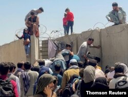 Un hombre lanza a una niña para entrar al aeropuerto internacional Hamid Karzai de Kabul, el lunes 16 de agosto de 2021.