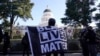 Un manifestante se cubre con una bandera del movimiento Black Lives Matter durante una protesta frente al Capitolio estatal en Sacramento, California, el 20 de enero de 2021.