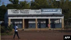 FILE - A man walks past a closed down butcher shop and liquor store amid the coronavirus pandemic, in Gaborone, Botswana, April 5, 2020.