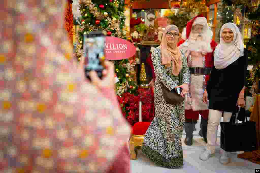 دو زن مسلمان در پایتخت مالزی با بابانوئل عکس یادگاری می‌گیرند. 
