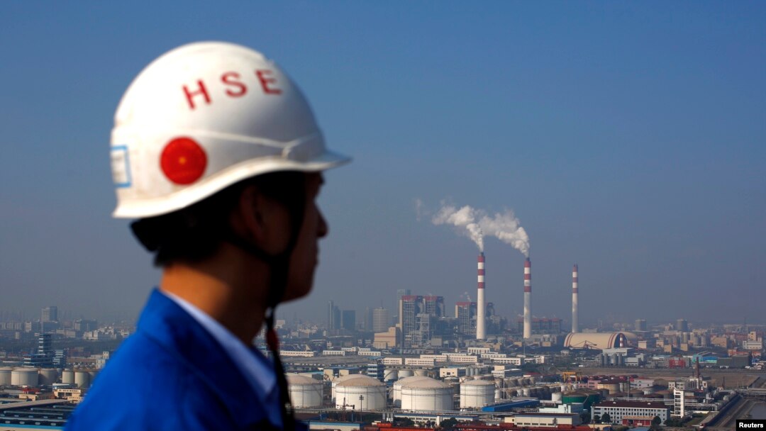 Smoke rises from the chimneys of a thermal power plant as a worker stands on a crane at a shipyard in Shanghai, Nov. 5, 2013. 