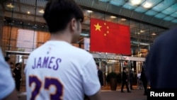 Seorang pria mengenakan kaus dengan nama dan nomor punggung LeBron James, pebasket Los Angeles Lakers, berdiri di luar Hotel Ritz-Carlton, di Shanghai, China, 9 Oktober 2019. (Foto: Reuters)