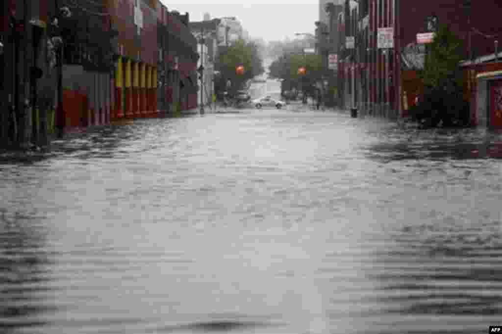 A police officer is parked at the end of a flooded street in Brooklyn, New York, Sunday, Aug. 28, 2011. Seawater surged into the streets of Manhattan on Sunday as Tropical Storm Irene slammed into New York, downgraded from a hurricane but still unleashing