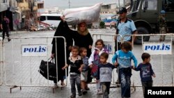 A Syrian family walks past a blast site in the town of Reyhanli of Hatay province near the Turkish-Syrian border May 12, 2013.