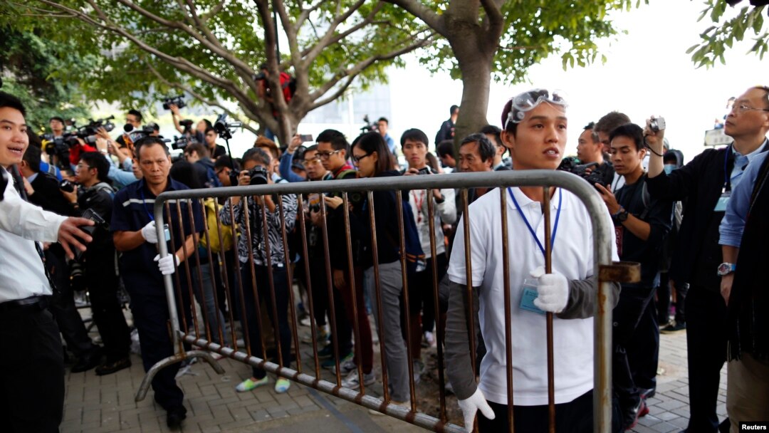 Demonstran pro-demokrasi (kanan) dan seorang pekerja memindahkan pagar sesuai perintah pengadilan untuk membersihkan tempat demonstrasi di Hong Kong (18/11).