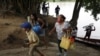 Una familia venezolana lleva sus pertenencias luego de cruzar el río Arauca en bote para salir de Venezuela, en Arauquita, Colombia. Marzo 25, 2021. Foto: AP.