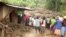 Residents watch flood waters pass through destroyed homes, after a landslide in Bududa, Uganda, in this still image taken from video, Oct. 12, 2018.