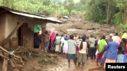 Penduduk mengamati aliran air akibat banjir yang menghanyutkan rumah mereka yang hancur pasca tanah longsor di Bududa, Uganda, 12 Oktober 2018.